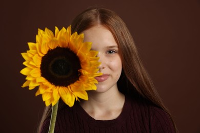 Photo of Teenage girl with beautiful sunflower on brown background