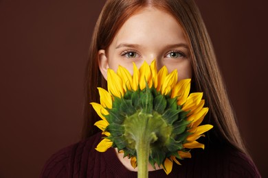 Photo of Teenage girl with beautiful sunflower on brown background