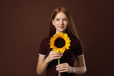 Photo of Teenage girl with beautiful sunflower on brown background