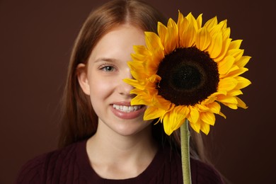 Photo of Teenage girl with beautiful sunflower on brown background