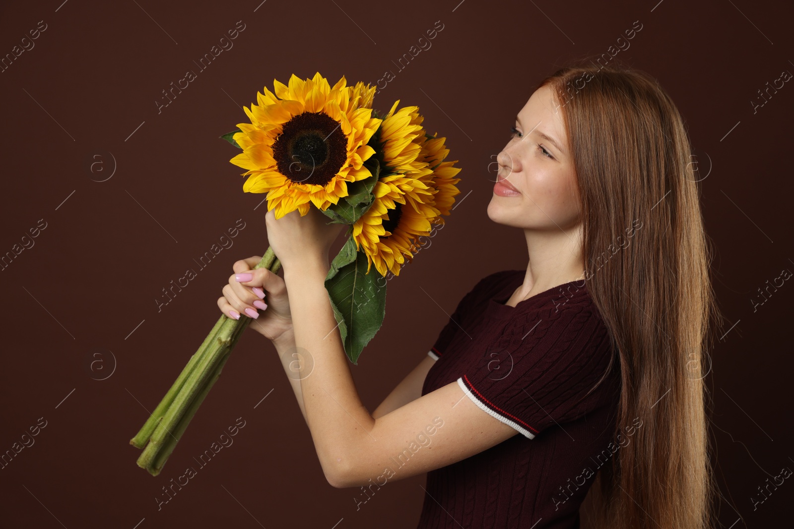 Photo of Teenage girl with bouquet of beautiful sunflowers on brown background