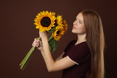 Photo of Teenage girl with bouquet of beautiful sunflowers on brown background