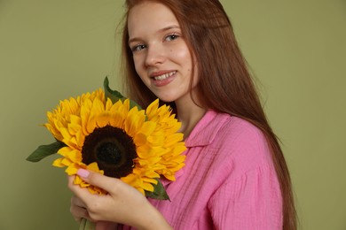 Photo of Teenage girl with beautiful sunflowers on green background