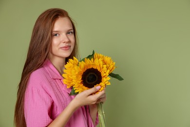 Photo of Teenage girl with beautiful sunflowers on green background, space for text