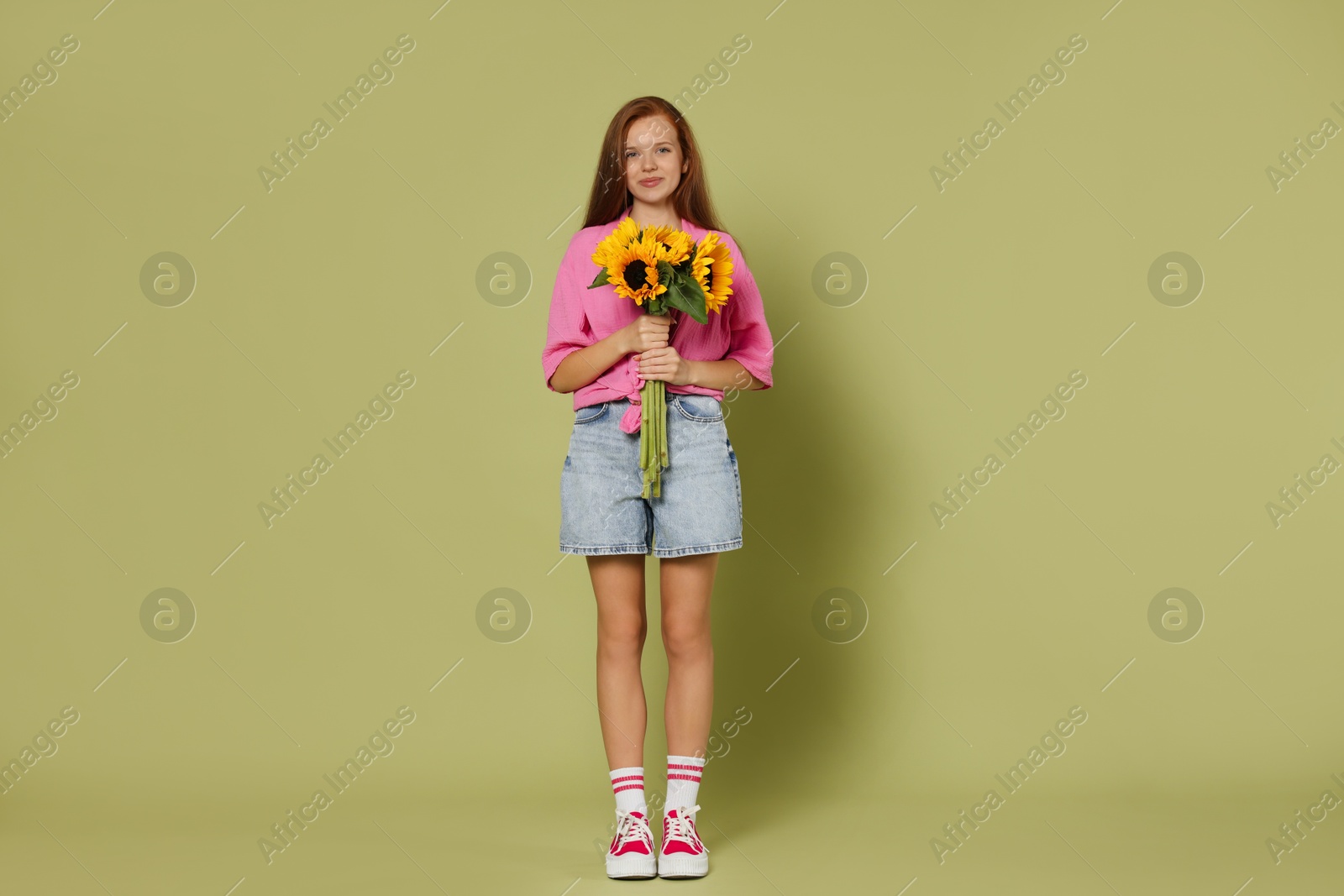 Photo of Teenage girl with bouquet of beautiful sunflowers on green background