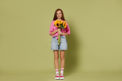 Photo of Teenage girl with bouquet of beautiful sunflowers on green background