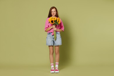 Photo of Teenage girl with bouquet of beautiful sunflowers on green background