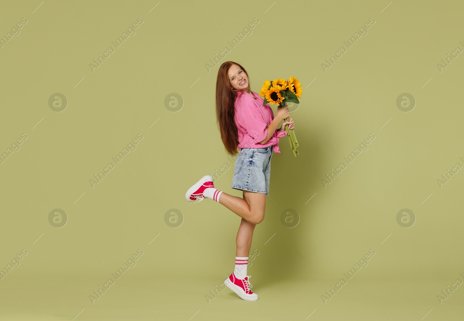 Photo of Teenage girl with bouquet of beautiful sunflowers on green background