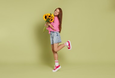 Photo of Teenage girl with bouquet of beautiful sunflowers on green background