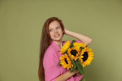 Photo of Teenage girl with bouquet of beautiful sunflowers on green background