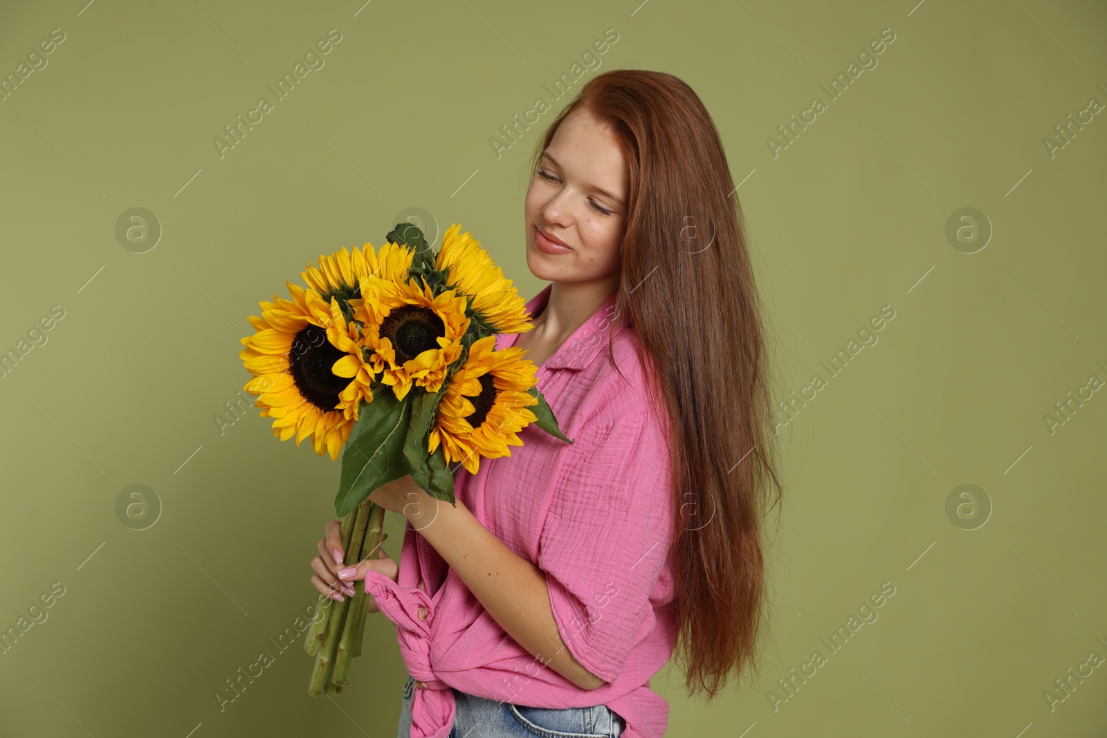 Photo of Teenage girl with bouquet of beautiful sunflowers on green background
