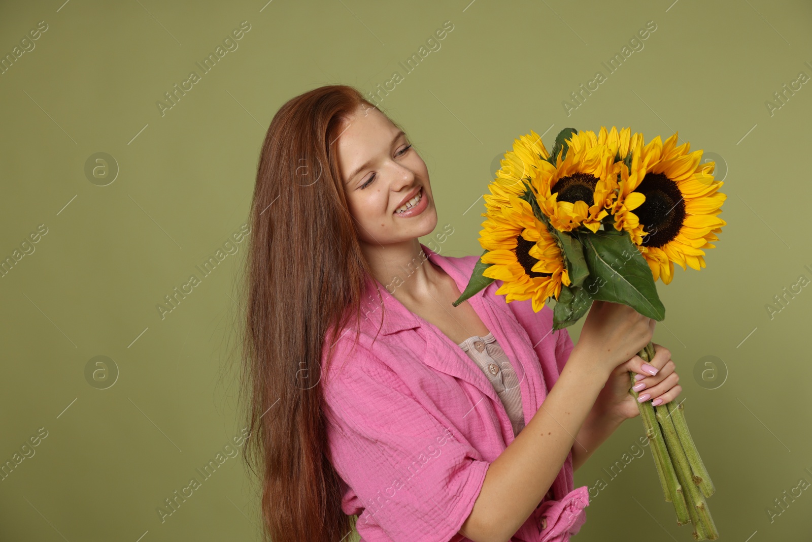 Photo of Teenage girl with bouquet of beautiful sunflowers on green background