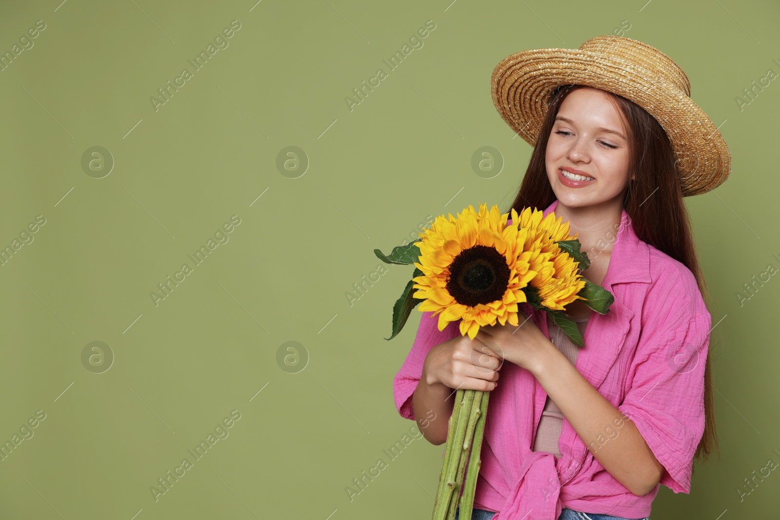 Photo of Teenage girl with beautiful sunflowers on green background, space for text