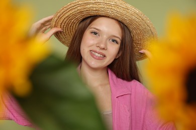 Photo of Teenage girl with beautiful sunflowers on green background, selective focus