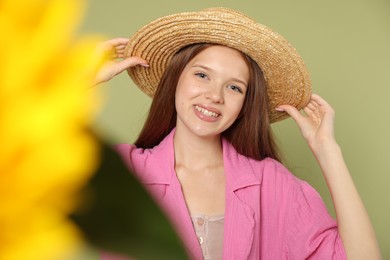 Photo of Teenage girl with beautiful sunflower on green background, selective focus