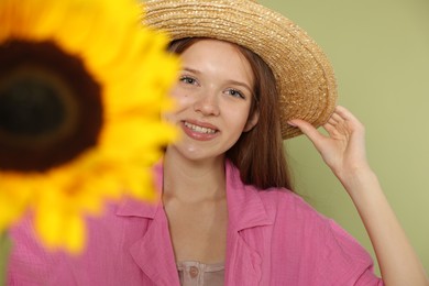 Photo of Teenage girl with beautiful sunflower on green background, selective focus