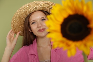Photo of Teenage girl with beautiful sunflower on green background, selective focus