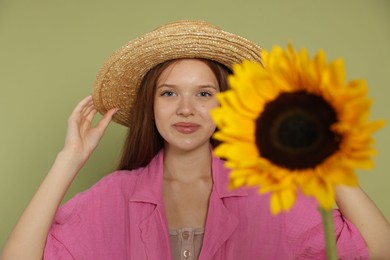 Photo of Teenage girl with beautiful sunflower on green background, selective focus