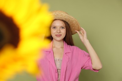 Photo of Teenage girl with beautiful sunflower on green background, selective focus