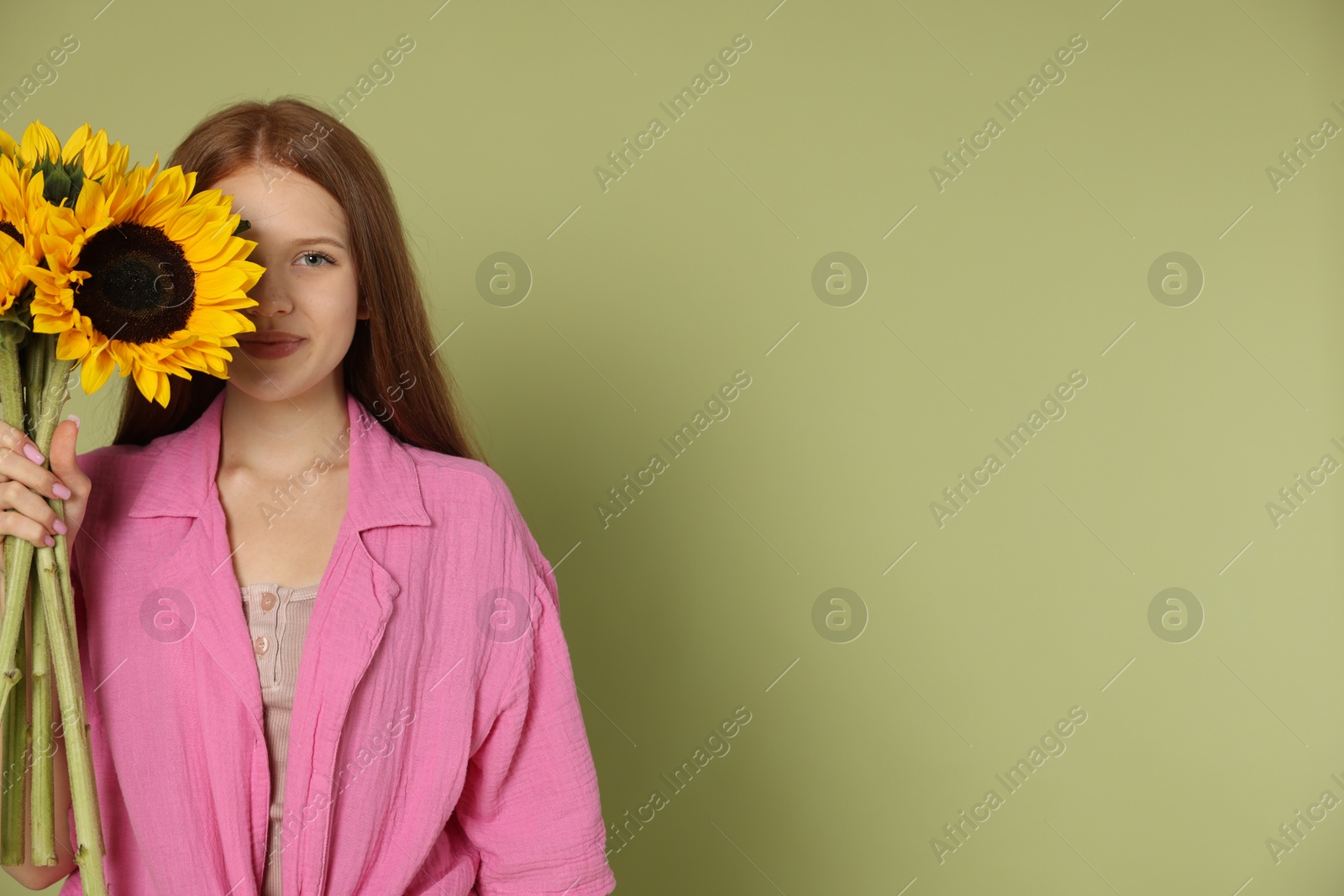 Photo of Teenage girl with beautiful sunflowers on green background, space for text