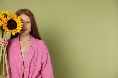 Photo of Teenage girl with beautiful sunflowers on green background, space for text