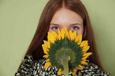 Photo of Teenage girl with beautiful sunflower on green background