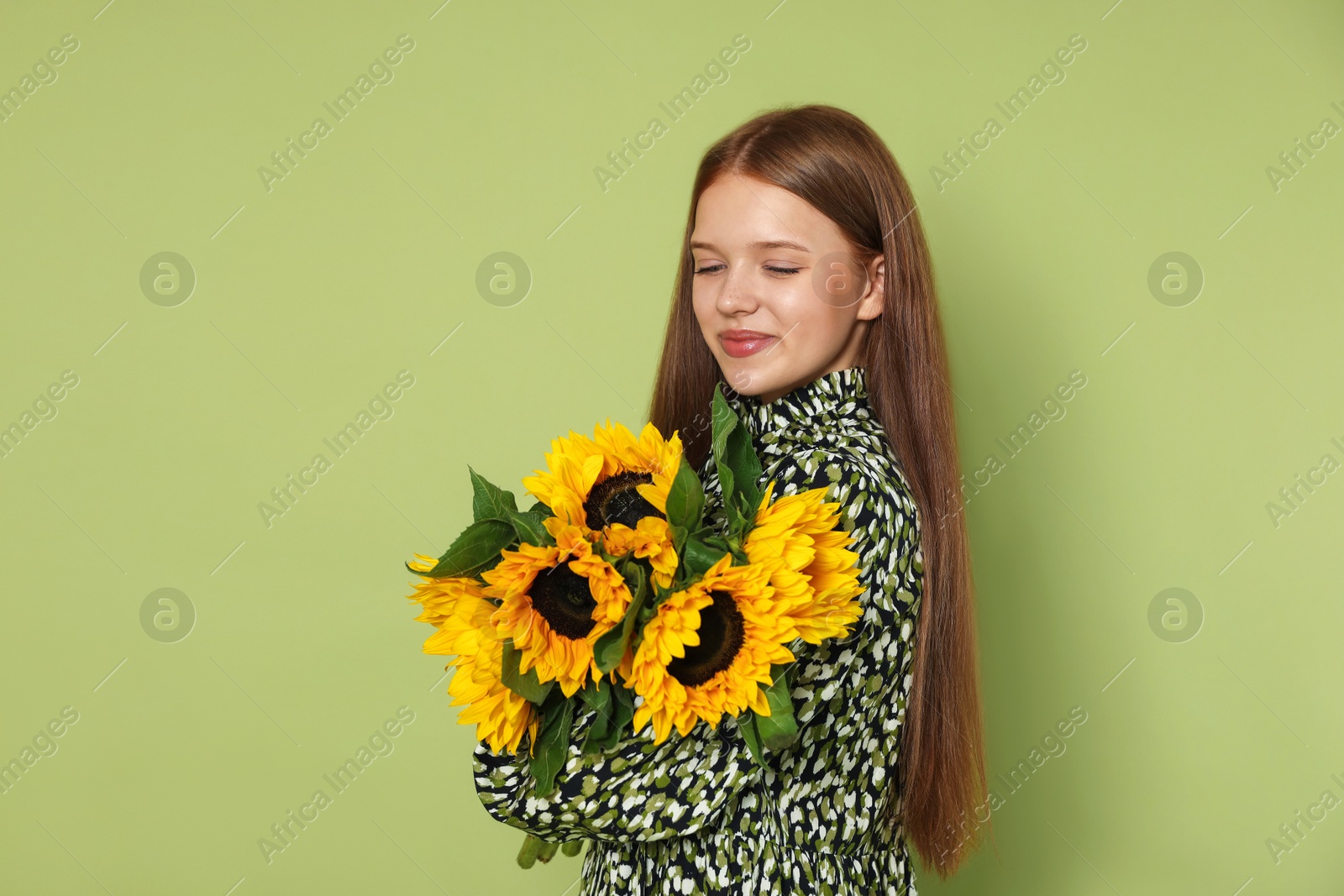 Photo of Teenage girl with bouquet of beautiful sunflowers on green background