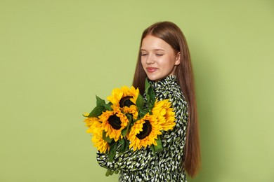 Photo of Teenage girl with bouquet of beautiful sunflowers on green background