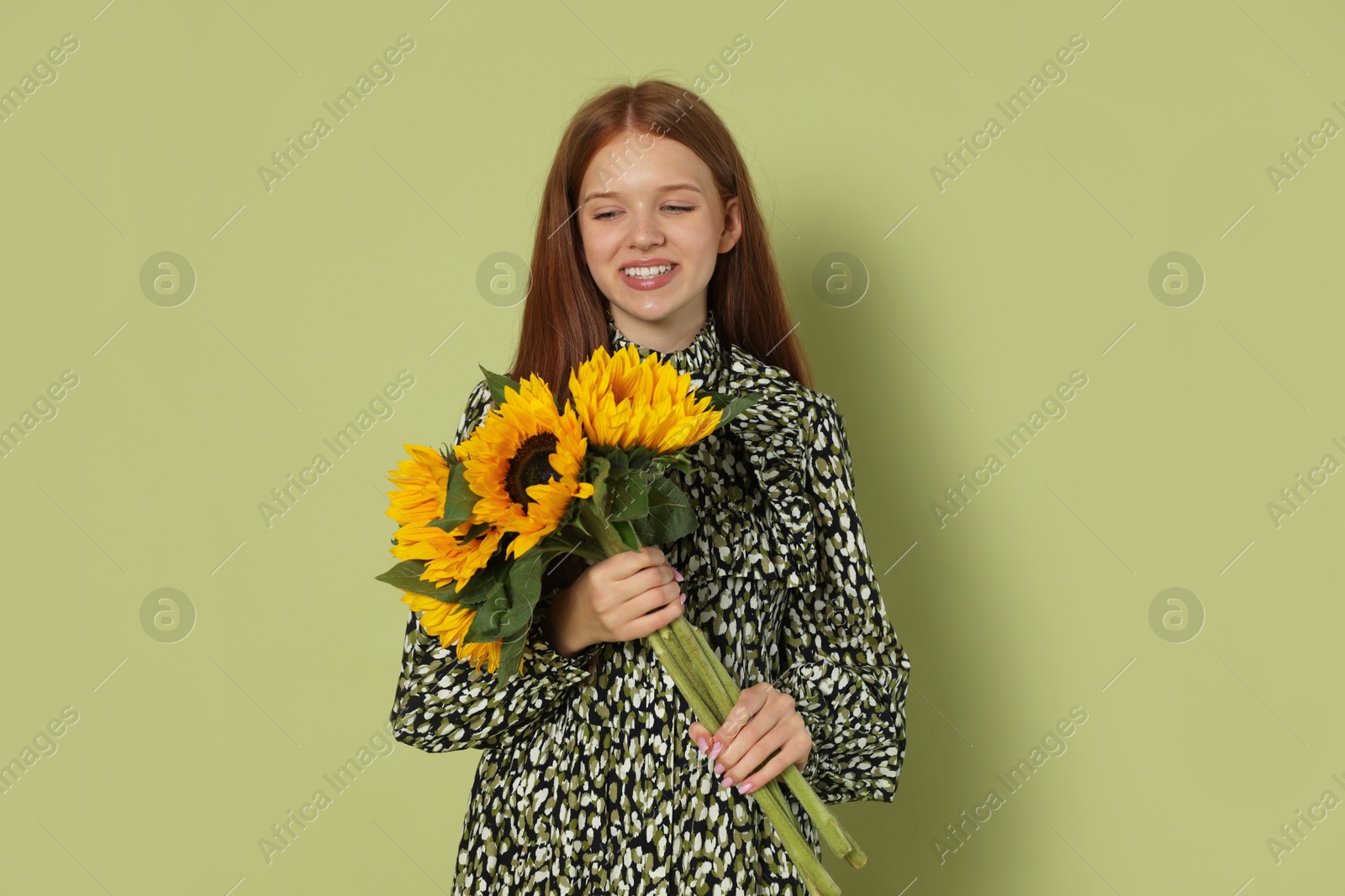 Photo of Teenage girl with bouquet of beautiful sunflowers on green background