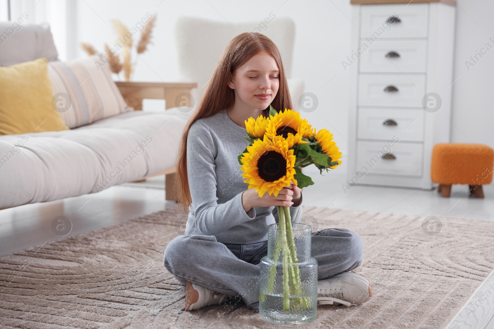 Photo of Teenage girl with beautiful sunflowers at home