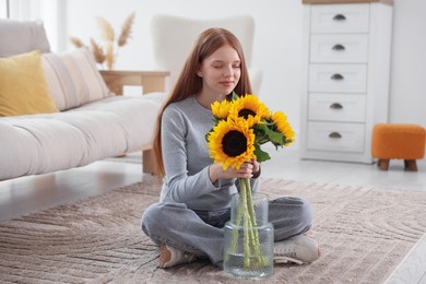Photo of Teenage girl with beautiful sunflowers at home