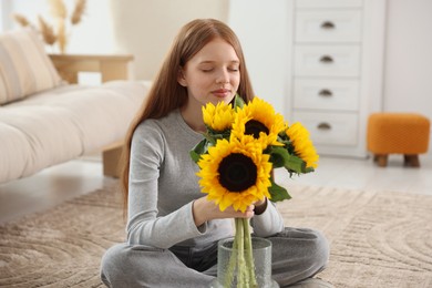 Photo of Teenage girl with beautiful sunflowers at home