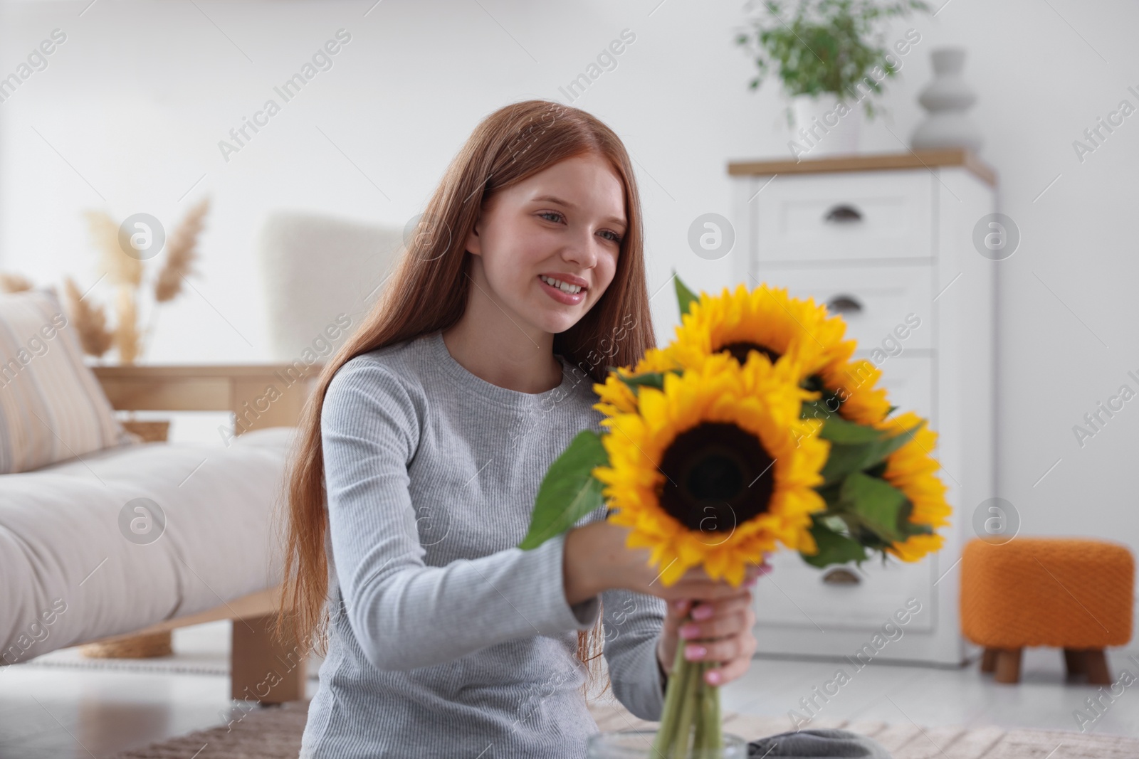 Photo of Teenage girl with beautiful sunflowers at home