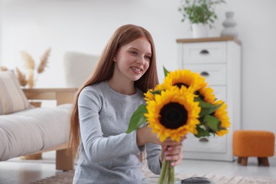 Photo of Teenage girl with beautiful sunflowers at home