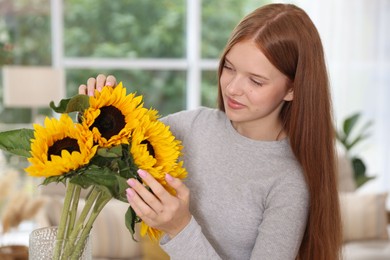 Photo of Teenage girl with beautiful sunflowers at home