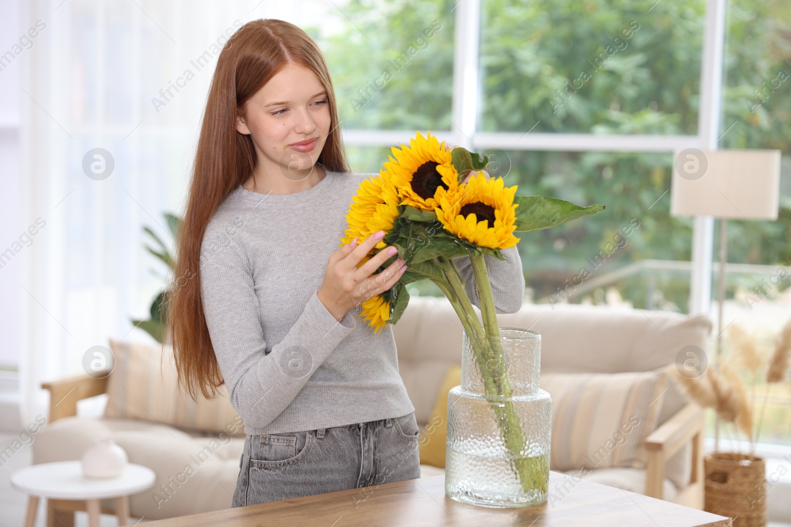 Photo of Teenage girl with beautiful sunflowers at home
