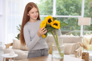 Photo of Teenage girl with beautiful sunflowers at home
