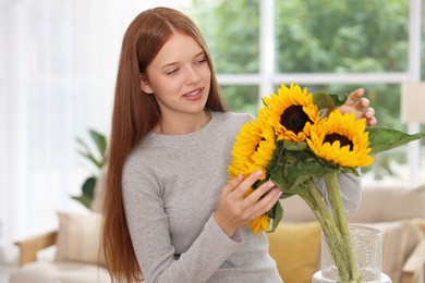 Photo of Teenage girl with beautiful sunflowers at home