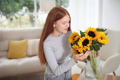 Photo of Teenage girl with beautiful sunflowers at home, space for text