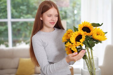 Photo of Teenage girl with beautiful sunflowers at home