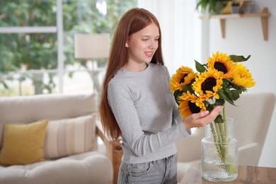 Photo of Teenage girl with beautiful sunflowers at home, space for text