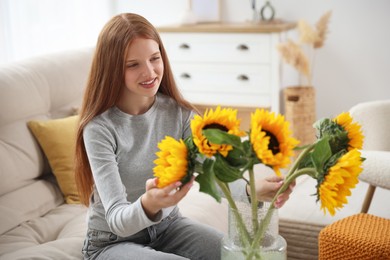 Photo of Teenage girl with beautiful sunflowers at home