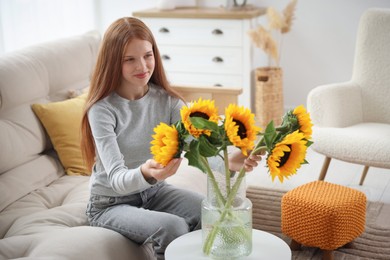 Photo of Teenage girl with beautiful sunflowers at home