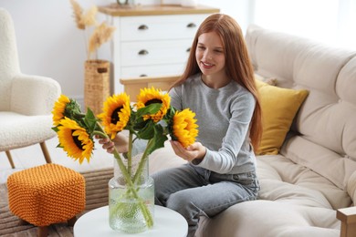 Photo of Teenage girl with beautiful sunflowers at home