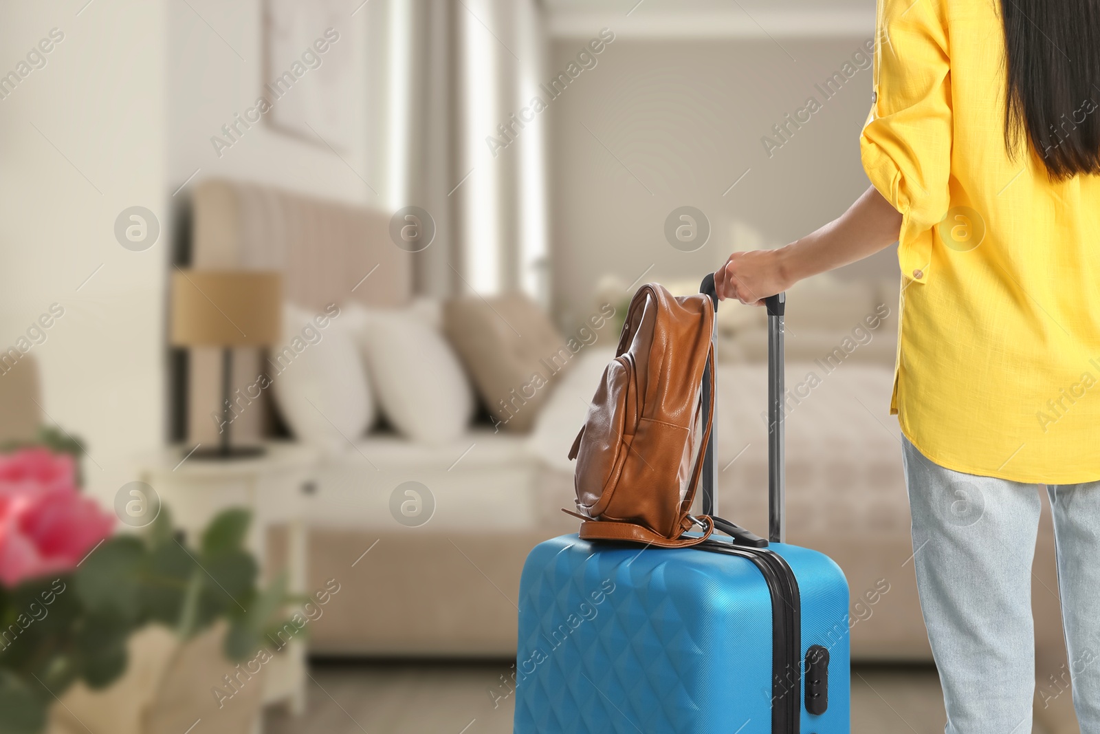 Image of Woman with suitcase and backpack in hotel room, closeup