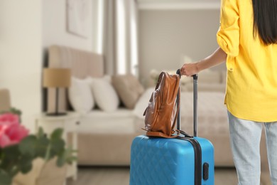 Image of Woman with suitcase and backpack in hotel room, closeup