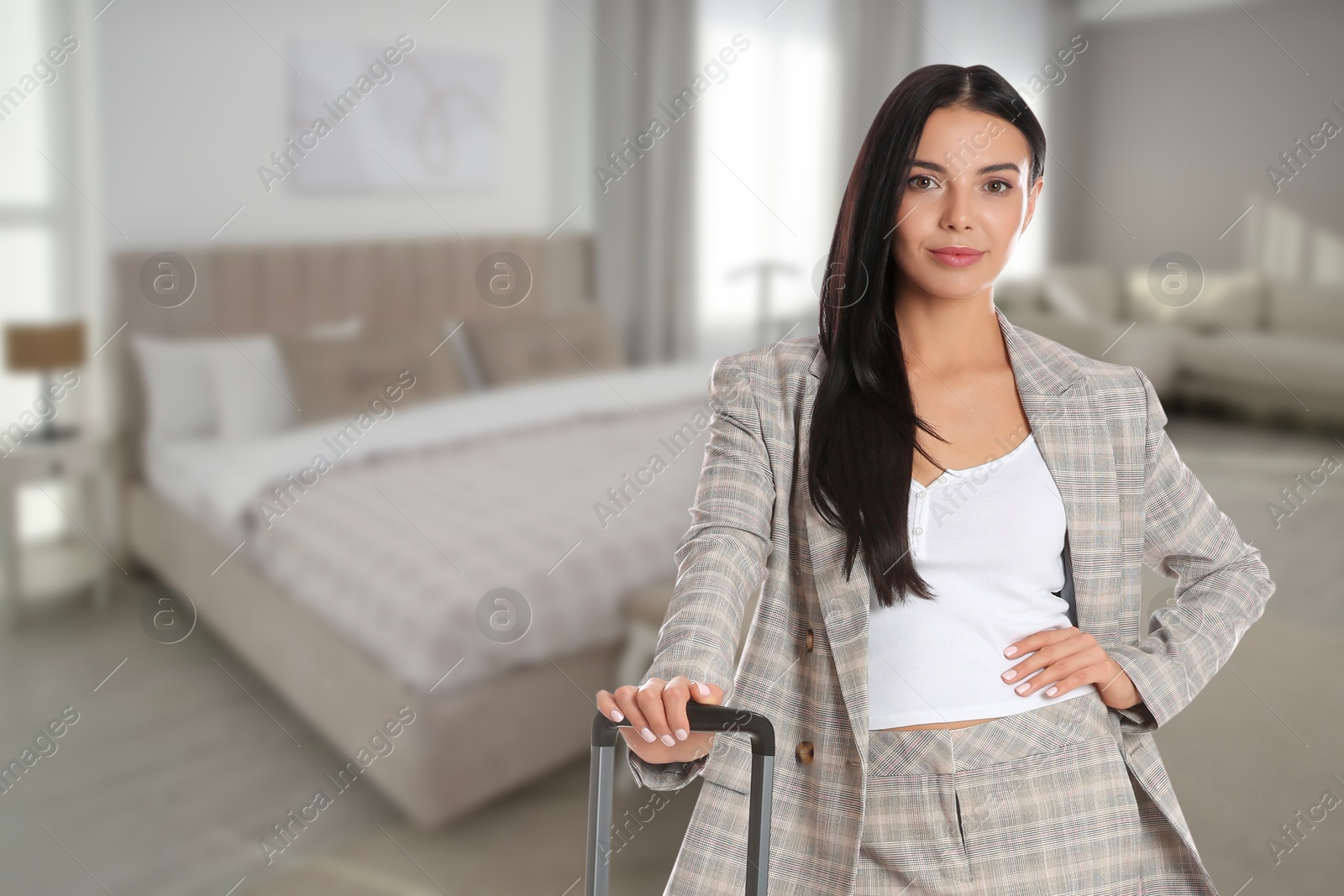 Image of Woman with suitcase near bed in hotel room