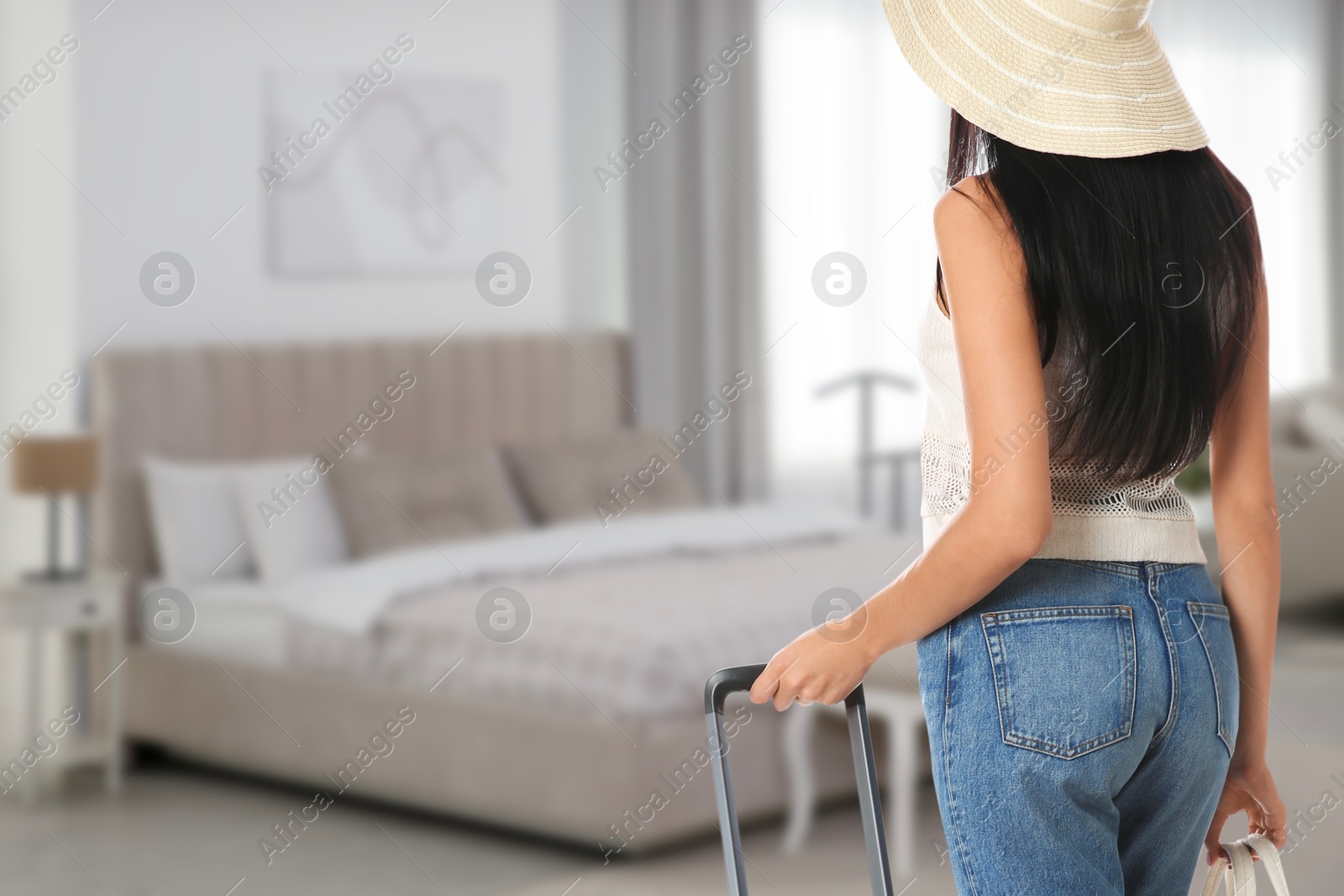 Image of Woman with suitcase and bag in hotel room. Guest heading to bed