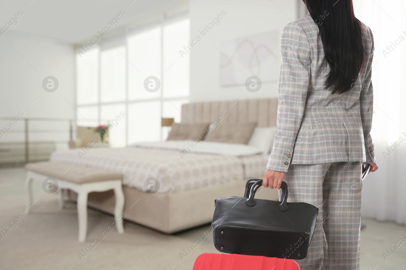 Image of Woman with suitcase and bag in hotel room
