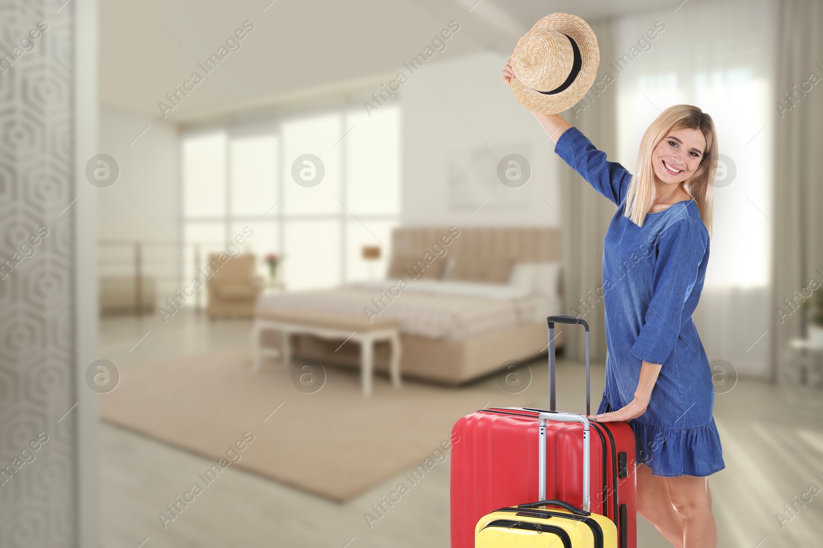 Image of Happy woman with suitcases in hotel room
